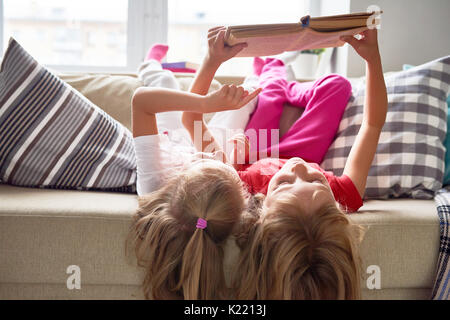 Les petites filles lecture livre à la maison Banque D'Images