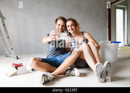 Couple à la peinture des murs, en tenant avec selfies smartphone. Banque D'Images