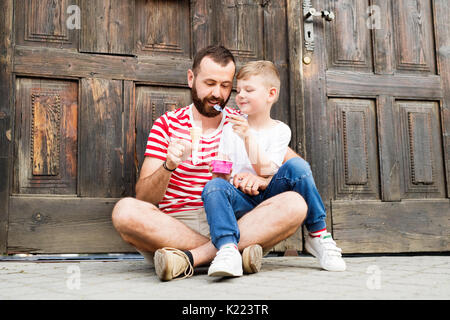 Jeune père et son petit-fils la consommation de crème glacée. Journée ensoleillée. Banque D'Images