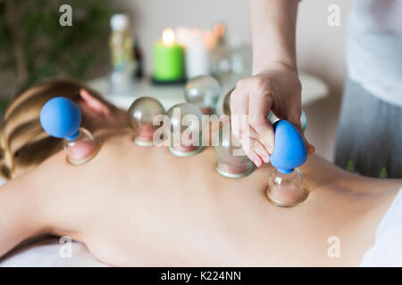 Jeune femme en traitement à la clinique médicale. fire cupping tasses à l'arrière du patient de sexe féminin en acupuncture therapy Banque D'Images