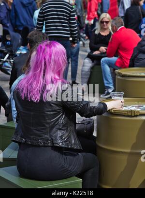 Femme aux cheveux roses, assis et tenant le verre de bière sur la table du fourreau Banque D'Images