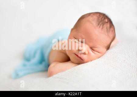 Bébé nouveau-né garçon, dormir paisiblement enveloppée d'enrubannage en tricot Banque D'Images