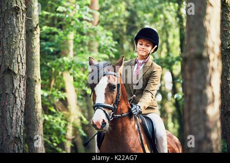 Adolescente dans l'usure formelle à cheval en forêt. Banque D'Images