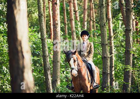 Adolescente dans l'usure formelle à cheval en forêt. Banque D'Images