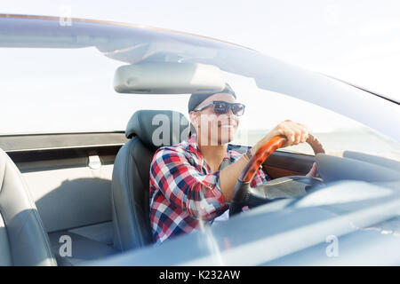 Happy young man driving convertible car Banque D'Images