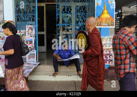 01.10.2013, Yangon, République de l'Union du Myanmar, de l'Asie - Un homme est vu assis sur le trottoir de la lecture d'un journal. Banque D'Images