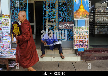 01.10.2013, Yangon, République de l'Union du Myanmar, de l'Asie - Un homme est vu assis sur le trottoir de la lecture d'un journal. Banque D'Images