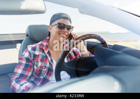 Homme heureux appelant sur smartphone en voiture décapotable Banque D'Images