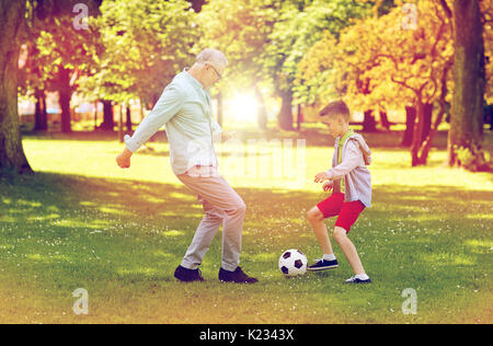 Vieil homme et garçon jouant au football au parc d'été Banque D'Images