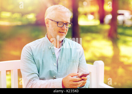 Happy senior man texting on smartphone à l'été Banque D'Images