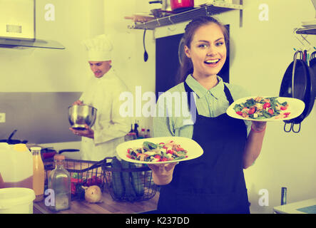 Portrait of beautiful smiling woman wearing apron serveuse et tenant prêt à servir la salade Banque D'Images