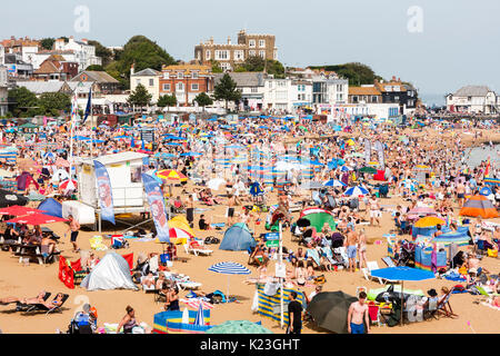 L'Angleterre, Viking Bay, Broadstairs. Totalement emballé avec plage-soleil d'asile pendant la période de temps chaud. Plage mer en vue, des masses de gens sur la plage. Un soleil brillant. Bleak House donnant sur la baie. Banque D'Images