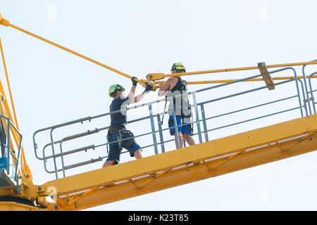 Les travailleurs dans le processus de retrait d'un démontage de grue à tour il bit par bit. Deux vis de liaison câble avant les articles sont supprimés. Banque D'Images