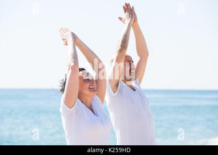 Mature Woman performing yoga sur la plage de sable. Focus on woman Banque D'Images