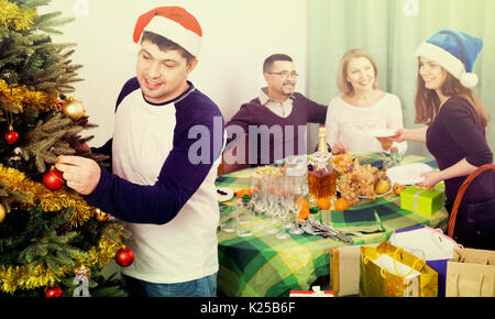 Happy smiling family configuration table pour diner, decorating Christmas Tree Banque D'Images