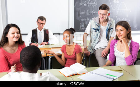 Heureux les étudiants de différentes nationalités assis et parler en classe alors que la pause Banque D'Images