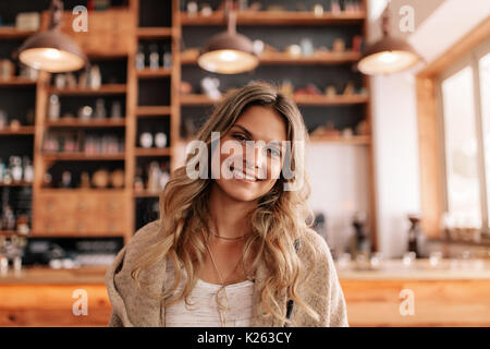 Portrait de belle jeune femme debout dans un café. Les jeunes femmes de race blanche dans un café à la caméra et au sourire. Banque D'Images