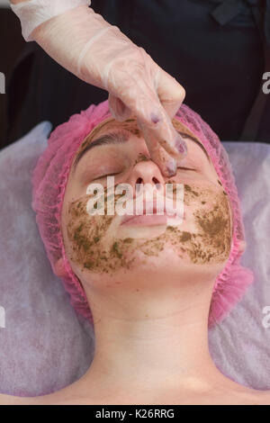 Jeune femme, corail face peeling. La main est l'application de masque facial. Banque D'Images