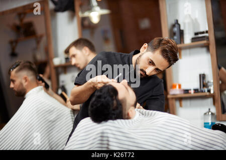 Deux stylistes, ce pain coupe coupe pour les clients dans un salon de coiffure. Banque D'Images