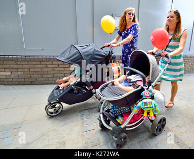 Londres, Angleterre, Royaume-Uni. Deux jeunes mères avec enfants en poussette et des ballons Banque D'Images