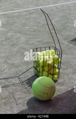 Les balles de tennis dans un panier métallique sur la cour. Banque D'Images