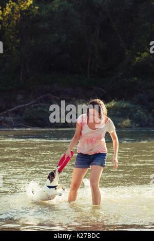 Femme jouant avec le chien dans l'eau Banque D'Images