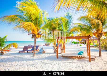 Des chaises longues sous un parasol sur la plage de sable Banque D'Images