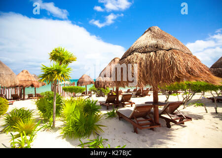 Des chaises longues sous un parasol sur la plage de sable Banque D'Images