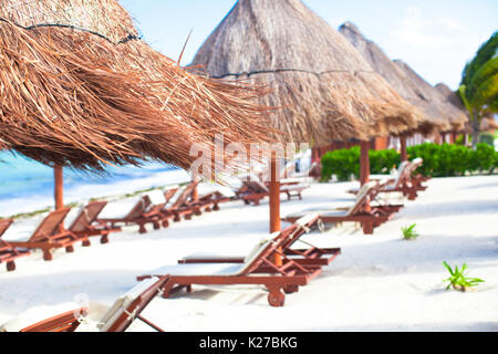 Des chaises longues sous un parasol sur la plage de sable Banque D'Images