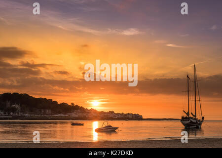 Le soleil se couche derrière le village de Appledore comme la marée roule la plage à Instow dans le Nord du Devon. Banque D'Images