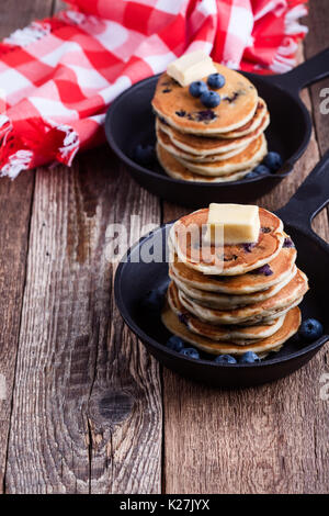 Crêpes de bleuets frais garni de beurre dans la poêle en fonte pour le brunch romantique servi sur table rustique Banque D'Images