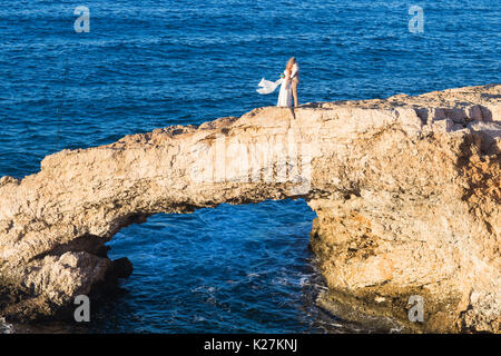 Élégant smiling young Couple marchant sur la plage, s'embrasser et s'amuser, cérémonie de mariage près de la roche et l'océan. Banque D'Images