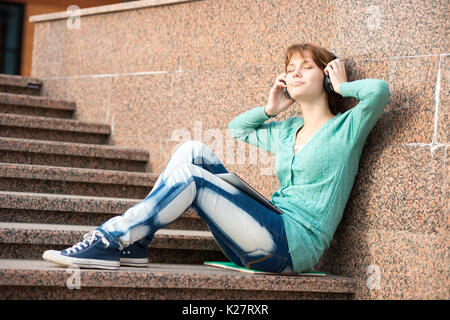 Belle jeune femme étudiant avec des écouteurs. Fille de musique en plein air Banque D'Images