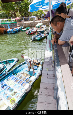 HONG KONG - le 13 juillet 2017 : un groupe de clients au Sai Kung pier l'achat des fruits de mer vivants d'un pêcheur en barque le long du port de Sai Kung fl Banque D'Images