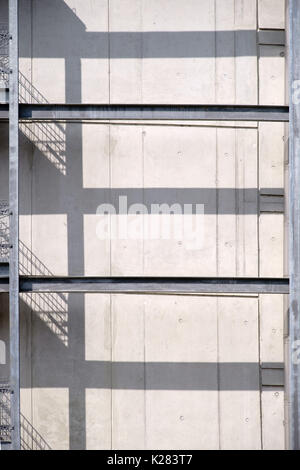 Un garde-corps en acier avec un escalier extérieur symétrique jette des ombres sur un mur de béton. Banque D'Images