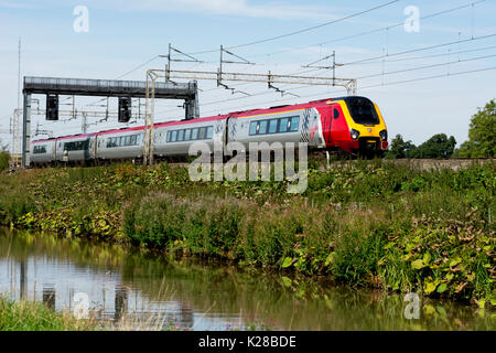 Virgin Trains Voyager sur la ligne principale de la côte ouest le long du canal d'Oxford, Ansty, Warwickshire, UK Banque D'Images