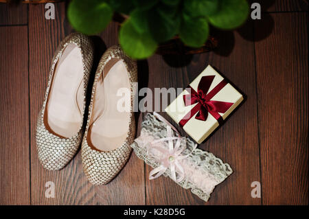 Photo en gros plan des chaussures de mariage, porte-jarretelles et petite boîte avec un ruban rouge. Banque D'Images