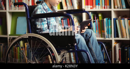 Mobilité schoolboy using digital tablet in library Banque D'Images