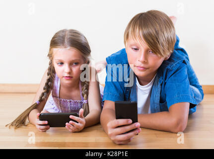 Des enfants heureux à l'écran à des smartphones modernes Banque D'Images