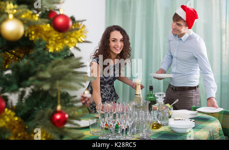 Happy smiling positive man and girl servant de table de Noël pour les clients dans la maison Banque D'Images