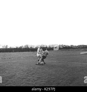 1964, historique, Angleterre, Royaume-Uni, deux homme sundaly les joueurs de football ligue amateur exigeant ou s'attaquer les uns les autres pour la balle. Banque D'Images