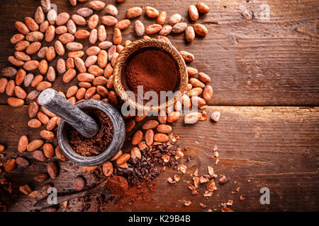 Concept de cacao avec mortier et pilon en pierre avec des matières, pelées et concassées, les fèves de cacao Theobroma cacao Banque D'Images