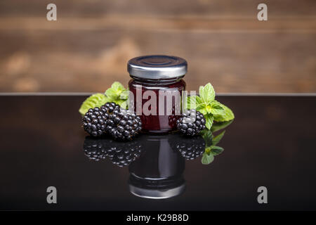 Confiture de mûres fraîches faites maison dans un bocal en verre sur une table en verre Banque D'Images