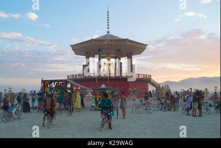 Brûleurs se réunissent autour de la statue de Burning Man au coucher du soleil sur la playa comme le désert Burning Man Festival annuel ferme le premier jour de la semaine 27 août 2017 Black Rock City, Nevada. Le festival annuel attire 70 000 visiteurs dans l'une des régions les plus isolées et les déserts inhospitaliers en Amérique. Banque D'Images