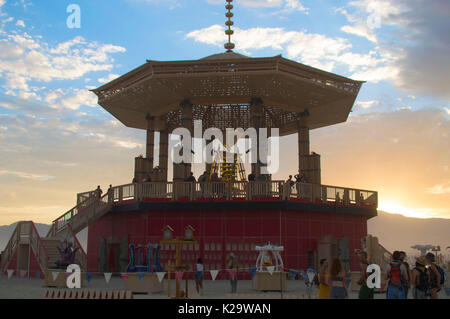 Brûleurs se réunissent autour de la statue de Burning Man au coucher du soleil sur la playa comme le désert Burning Man Festival annuel ferme le premier jour de la semaine 27 août 2017 Black Rock City, Nevada. Le festival annuel attire 70 000 visiteurs dans l'une des régions les plus isolées et les déserts inhospitaliers en Amérique. Banque D'Images