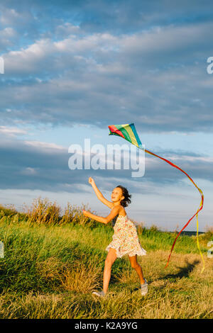 Cheerful girl running with kite Banque D'Images