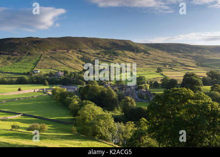 Pittoresque village ensoleillé de Burnsall dans la vallée de la rivière Wharfe (pentes à flanc de colline, hautes collines, champs verts, pâturages, ciel bleu) - Yorkshire Dales, Angleterre, Royaume-Uni. Banque D'Images