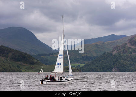 De collines et sous ciel gris, les gens sont dans de petits bateaux à voile sur Ullswater - voir à Glenridding et Penrith, Lake District, England, UK. Banque D'Images