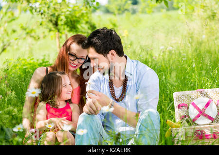 Family having picnic sur prairie avec des fruits sains Banque D'Images