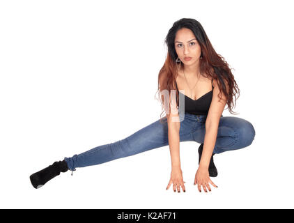 Une belle jeune femme slim en jeans et d'un corset noir accroupi sur le plancher, à la grave, pour isolé sur fond blanc Banque D'Images